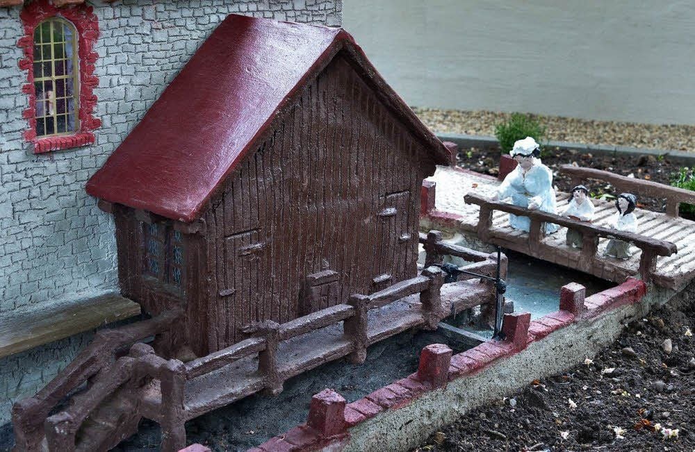 Die Müllersfrau schaut mit ihren Kindern ins Wasser.