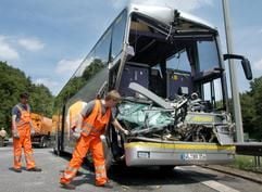 Ein Arbeiter zieht ein Trümmerteil aus einem an der Frontseite total zerstörten Bus nach einem Unfall auf der A 7 in Hamburg. (Foto: dpa)