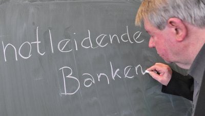 Der Sprecher der Jury für das «Unwort des Jahres», Horst Dieter Schlosser, schreibt in Frankfurt am Main das «Unwort des Jahres» für 2008 an eine Tafel. Es lautet «notleidende Banken». (FOTO: DPA)