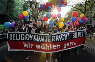 Demonstranten ziehen mit einem Plakat durch Berlin, auf dem «Religionsunterricht bildet. Wir wählen gern.» zu lesen ist. (FOTO: DPA)