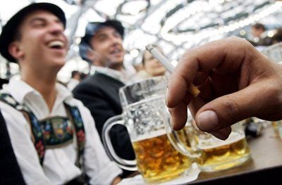 Männer in Trachten sitzen in einem Festzelt auf dem 175. Oktoberfest in München an einem Tisch, trinken Bier und rauchen. (Foto: dpa)