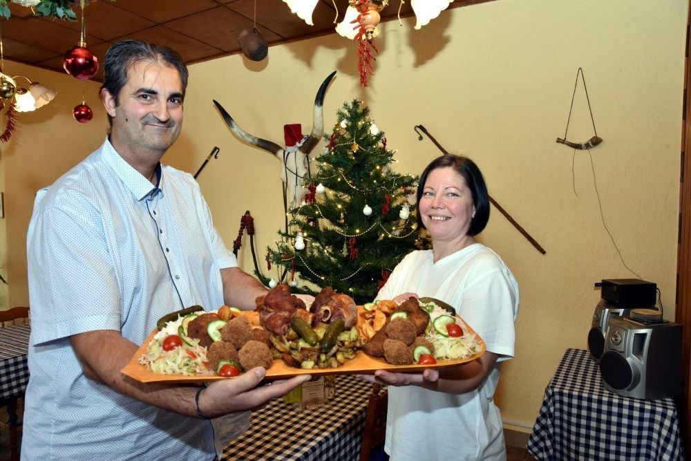 Krisztina Bartáné Olasz (rechts) und Csaba Barta mit einer Fleischplatte für zwei Personen. Sie zeigen den Betyar-Teller mit Eisbein, Schnitzel, Hackbraten, saurem Gemüse und Kartoffelspalten mit Reis, ungarischer Wurst und gebratenem Speck.