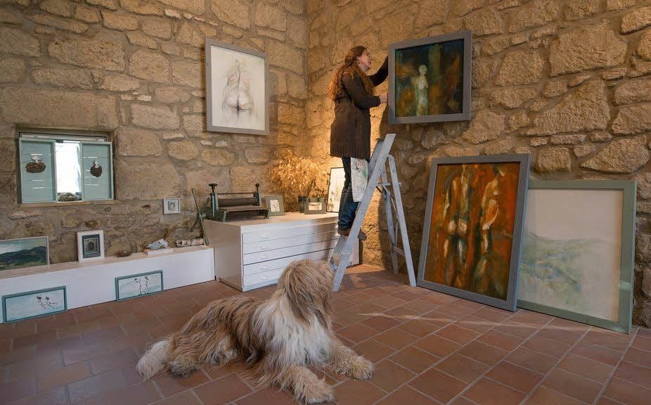 Anke Dilé Wissing hängt, beobachtet von Carlo, eines ihrer Bilder im neuen Atelier in der Pölkenstraße 51 auf.