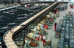 An einem so genannten Kippschalen-Sorter packen Mitarbeiter im Logistikzentrum der Dirk Rossmann GmbH in Landsberg Waren für den Versand. (Foto: dpa)