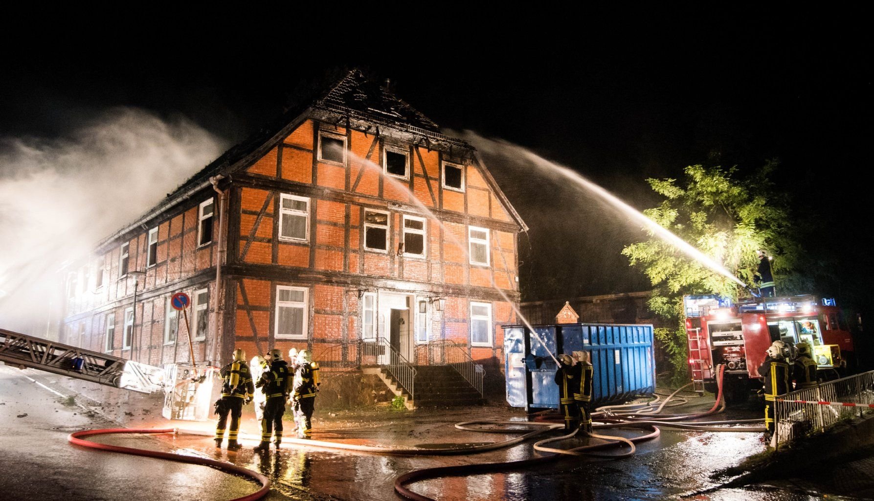 Feuerwehrleute löschen die brennende geplante Notunterkunft für Flüchtlinge.