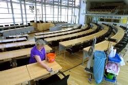 Eine Mitarbeiterin säubert die Tische des Plenarsaals im Landtag Sachsen-Anhalts in Magdeburg. (Foto: dpa)