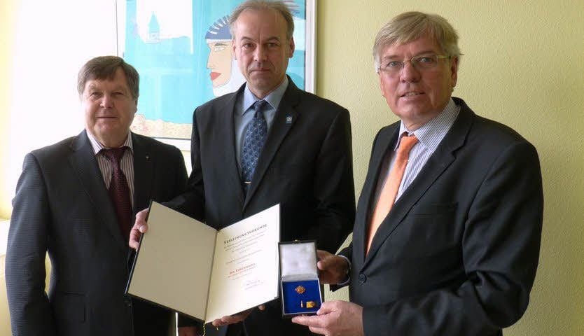 Dieter Steinecke (li.) und Hartmut Möllring (re.) überreichen Matthias Georg Beyersdorfer die Ehrennadel des Landes.
