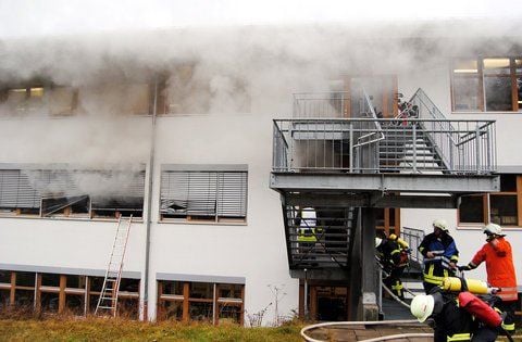 Feuerwehrmänner stehen in Titisee-Neustadt (Baden-Württemberg) während der Löscharbeiten vor einer Behindertenwerkstatt. 14 Menschen sind bei dem Brand ums Leben gekommen.