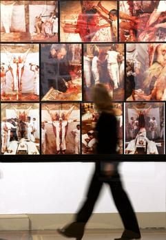 Eine Besucherin geht am Mittwoch (29.11.2006) im Berliner Martin-Gropius-Bau an einer Kollage mit Fotos von einer Aktion des Künstlers Hermann Nitsch vorbei. (Foto: dpa)