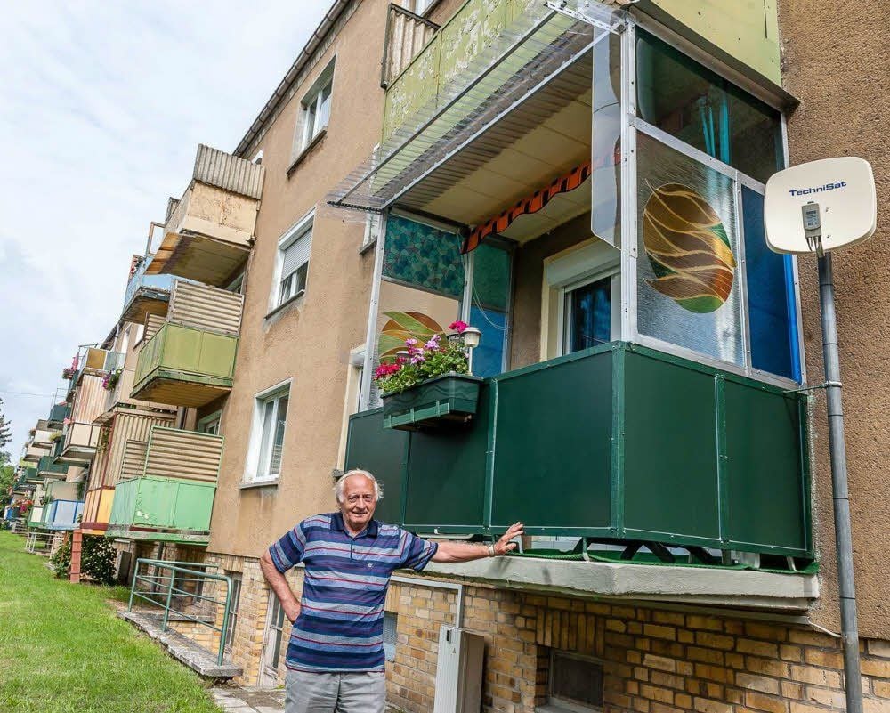 Günter Schulz vor seinem Balkon: Das Vordach und die Satellitenschüssel müssen weg, fordert der Vermieter. Schulz aber will das erst tun, wenn die anderen ihre Dächer und Schüsseln ebenfalls abmontieren.