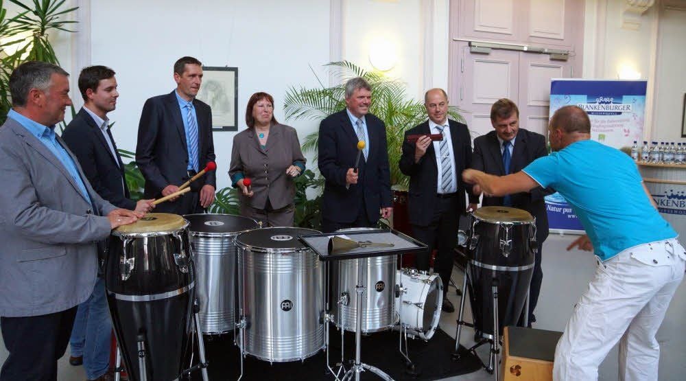 Die Landratskandidaten Carsten Nell, Tonio Schunk, Dirk Michelmann, Sabine Kolbe, Martin Skiebe, Michael Jäger und Heiko Kaschel (von links) trommeln auf den Instrumenten der Gruppe „Baraban“ aus Wernigerode, die die Podiumsdiskussion kulturell umrahmte, zur Landratswahl.