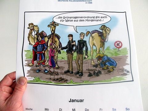 Die Januar-Karikatur des Kalenders zeigt zwei Polizisten in einer Grünanlage zusammen mit drei Männern mit Kamelen. (FOTO: DPA)