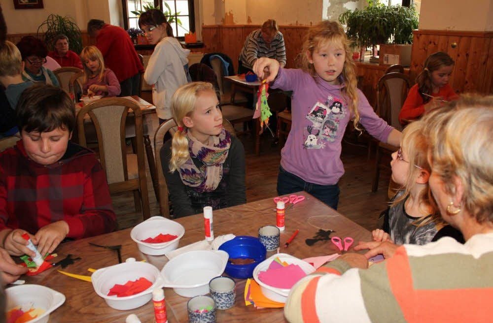 Annelie (sieben Jahre, Mitte) zeigt Finn (acht), Natalie (zwölf), Tanja (fünf) und der Caritas Mitarbeiterin Andrea Rejl (von links) in der Hofstube stolz ihren eben fertiggestellten kleinen Hampelmann.