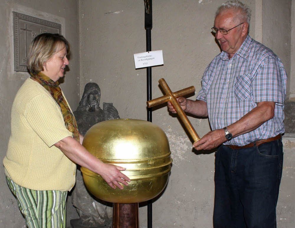 Ellen Heinichen vom Kirchspielrat Reuden begutachtet die Turmkugel und das Kreuz. Beides hat Herbert Mähler vergoldet.