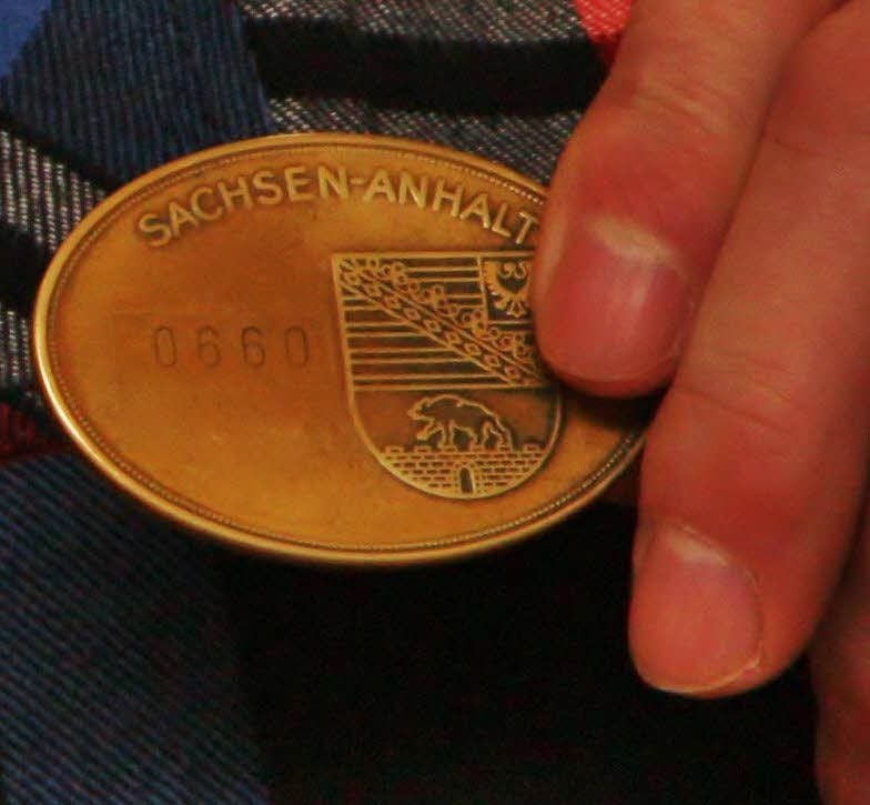 Blick auf die Dienstmarke eines Kriminalbeamten, die mit dem jeweiligen Landeswappen versehen ist.