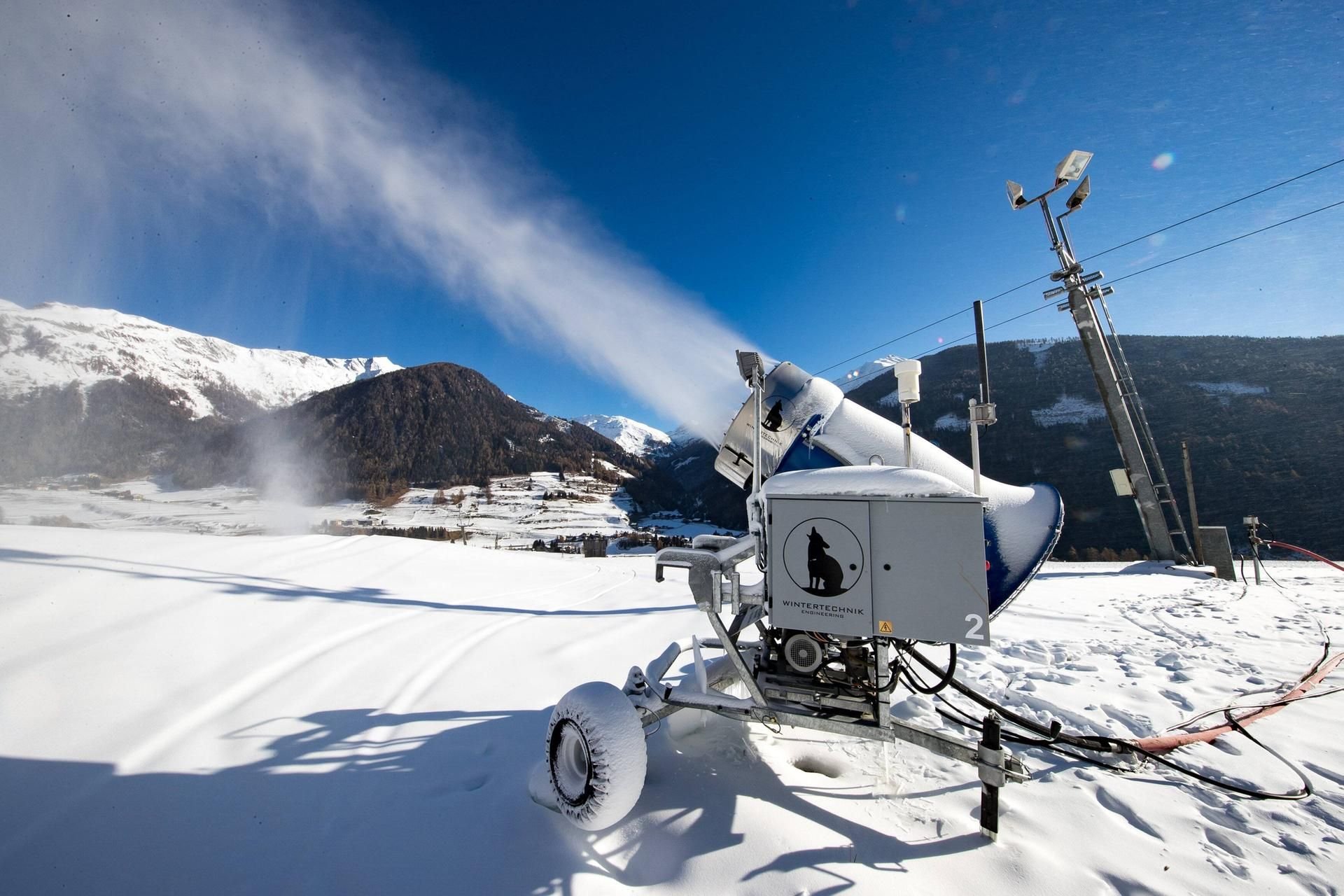 Eine Schneekanone beschneit künstlich einen Hang in Österreich.