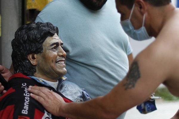 Ein Mann legt seine Hand auf eine Diego-Maradona-Statue im Stadtteil La Boca von Buenos Aires, nachdem er von seinem Tod erfahren hat.