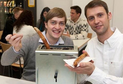 Der 25-jährige Ingenieur Felix Rennies (l.) und der 28-jährige Betriebswirt Marco Bruns präsentieren in ihrer Büroküche in Bremen einen von ihnen entwickelten «Wurst-Toaster». (FOTO: DAPD)