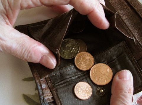 Eine Frau hält ein fast leeres Portemonnaie in den Händen.