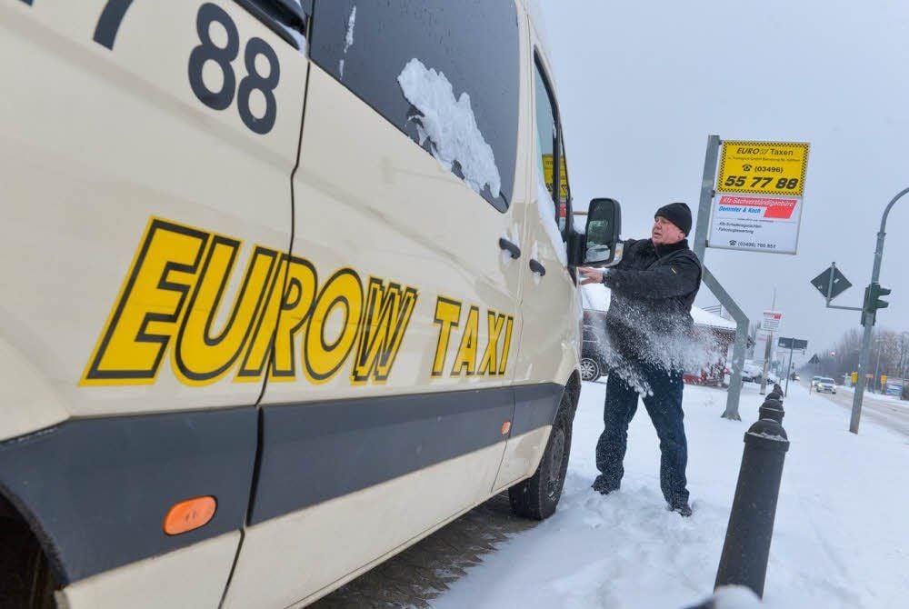 Vor dem Start muss Günter Schneider, Dispatcher und Fahrer bei Eurow-Taxen, erst einmal Schnee von seinem Taxi kehren.