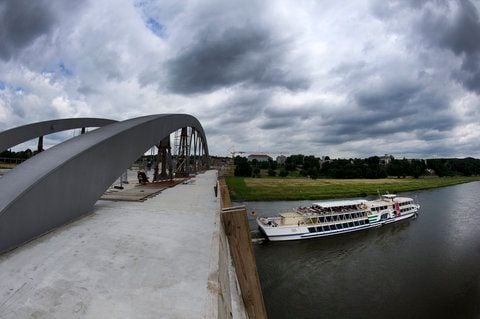 Ein Fahrgastschiff durchfährt die im Bau befindliche Waldschlößchenbrücke unterhalb des Waldschlößchens im Elbtal in Dresden.