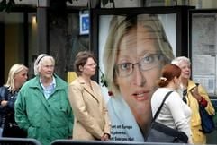 Passanten stehen in Gothenburg an einer Bushaltestelle vor dem Plakat der ermordeneten schwedischen Außenministerin Anna Lindh. (Foto: dpa)