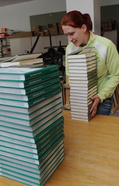 Josephine Boeters mit den fertigen Büchern. Das Verlagsprogramm umfasst unter anderem die Klassikerbibliothek (links).