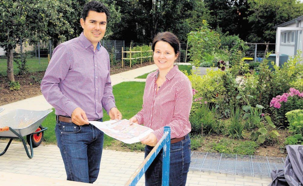 Zeigen den Bauplan und die WG-Anlage mit dem schönen Garten: Sandy und Alexander Scheunpflug. Sie sind die Investoren und Betreiber.