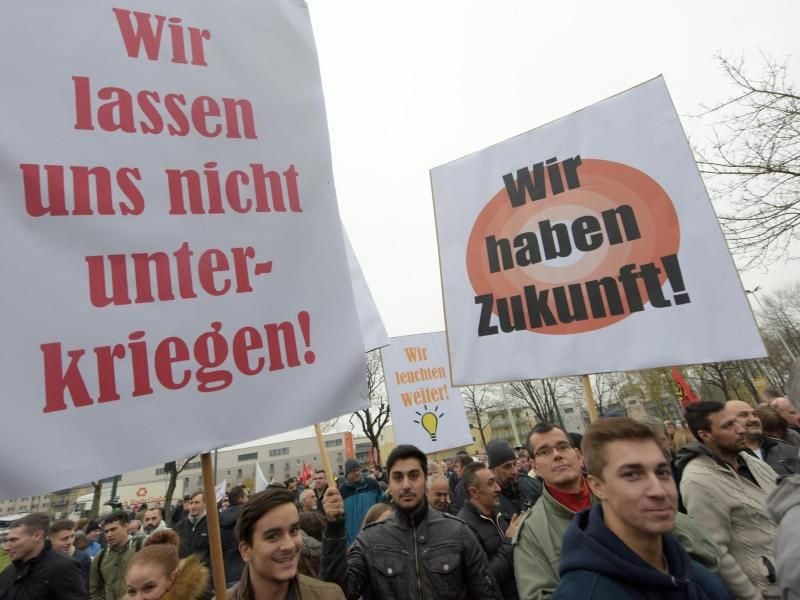 Mit Plakaten protestieren Mitarbeiter in Augsburg vor dem Werk des Lampenherstellers Ledvance gegen die Schließung der Fabrik. Foto: Stefan Puchner
