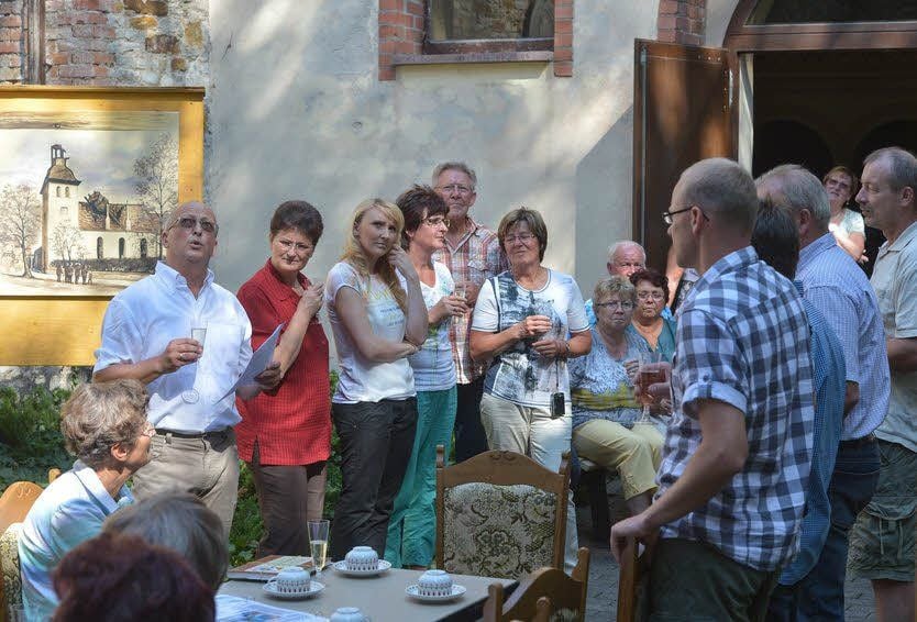 Vereinsvorsitzender Bernd Marschhausen (l. stehend) stößt mit den zahlreichen Gästen der Feier auf die Turmuhr an.