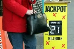 Eine Frau verlässt am Donnerstag (09.12.2004) eine Lottoannahmestelle in Kassel und passiert ein Hinweisschild auf den Jackpot. (Foto: dpa)