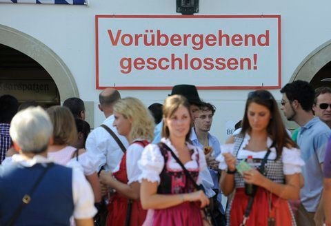 Besucher des Oktoberfests stehen vor einem geschlossenen Zelt. (FOTO: DPA)