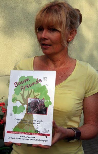 Prettins Grundschulleiterin Sylvie Ebermann zeigt die Baum-Urkunde: Ein Zierapfel wird gepflanzt.