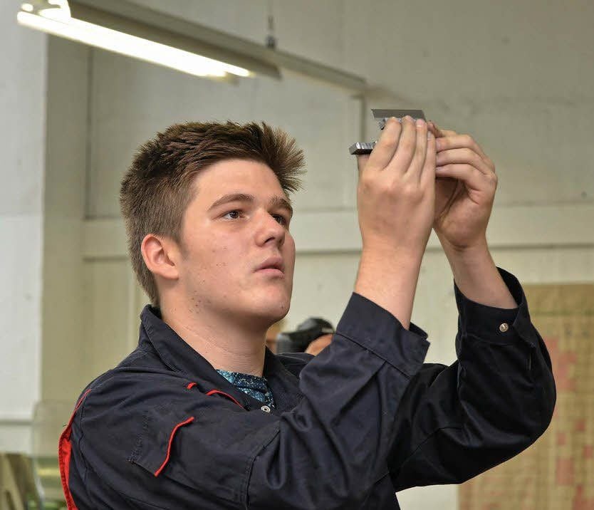 Oliver Drobe, 1. Lehrjahr, prüft in der Metallwerkstatt ein Werkstück.