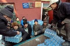 Nach dem Unfall in einer Chemiefabrik verteilen zwei Männer in der 3,2 Millionen-Einwohner-Stadt Harbin in China von einem Lkw aus Mineralwasser. (Foto: dpa)