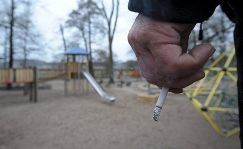 Auf einem Spielplatz hält ein Mann eine Zigarette in der Hand. (FOTO: DPA)