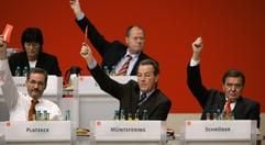 Bundeskanzler Gerhard Schröder (r), der SPD-Vorsitzender Franz Müntefering und der brandenburgische Ministerpräsident Matthias Platzeck (l), und Peer Steinbrück (hinten r.) stimmen am Montag (14.11.2005) in Karlsruhe beim SPD-Bundesparteitag für eine große Koaltion ab. Gesundheitsministerin Ulla Schmidt (hinten l.) liest in Unterlagen. (Foto: dpa)