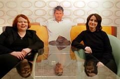 Die Designerinnen Susanne Schmidt (l) und Andrea Baum sitzen am Mittwoch (14.01.2003) in ihrer Mainzer Wohnung vor einer sogenannten Single-Tapete, auf der ein Mann abgebildet ist. Mit der ungewöhnlichen Idee, Menschen auf Tapeten abzubilden und damit Wohnungen für Singles freundlicher zu gestalten, kommen die jungen Frauen Mitte Januar auf den Markt. Um die 200 Euro sollen fünf Bahnen der Tapete, in der Größe von etwa drei mal zwei Meter kosten. (Foto: dpa)