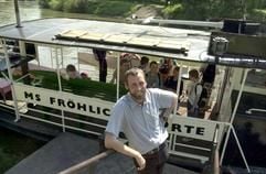 Der Fährmann Manfred Schmidt steht am Fährhafen "Blütengrund" in Großjena bei Naumburg vor dem Fahrgastschiff MS "Fröhliche Dörte" (Archivfoto vom 26.05.2000). Der 116 Jahre alte Dampfer war Anfang Mai in Freyburg bei einer Rettungsaktion für drei schiffbrüchige Schülerinnen und ihre Lehrerin gesunken. Das schwer beschädigte Fahrgastschiff wartet derzeit in der Werft in Dresden-Laubegast auf die Reparatur. (Foto: dpa)