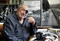 Lothar-Günther Buchheim, Schriftsteller, Künstler und Kunstsammler, lächelt in seinem Haus in Feldafing am Starnberger See vor Schwarzweiß-Fotos sitzend in die Kamera (Archivfoto vom 12.08.2004: dpa)