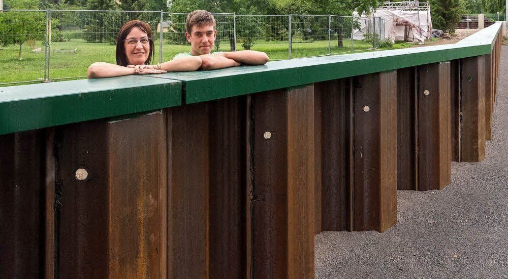 Eine Seite grün, die andere bleibt unbehandelt: Uta Stötzner und Sohn Jan stehen an der Hochwasserschutzwand in ihrem Garten.