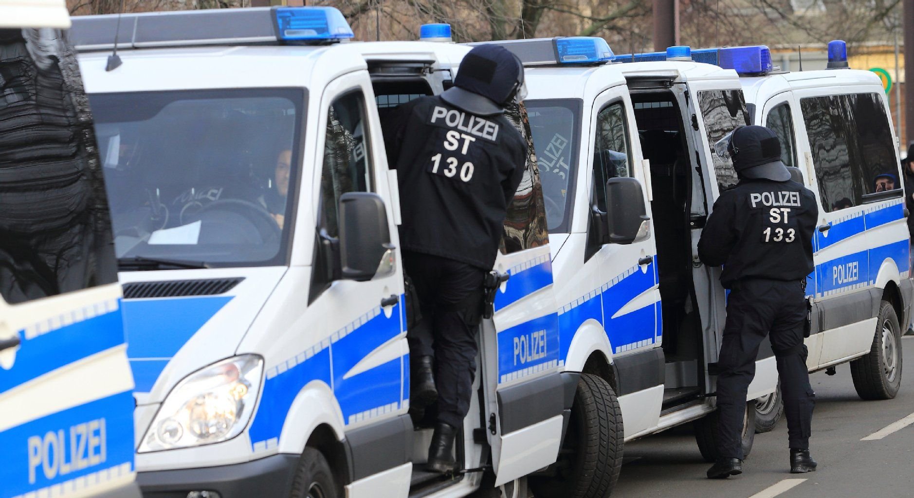 Polizisten stehen in Magdeburg während eines Einsatzes neben ihren Polizeiautos.