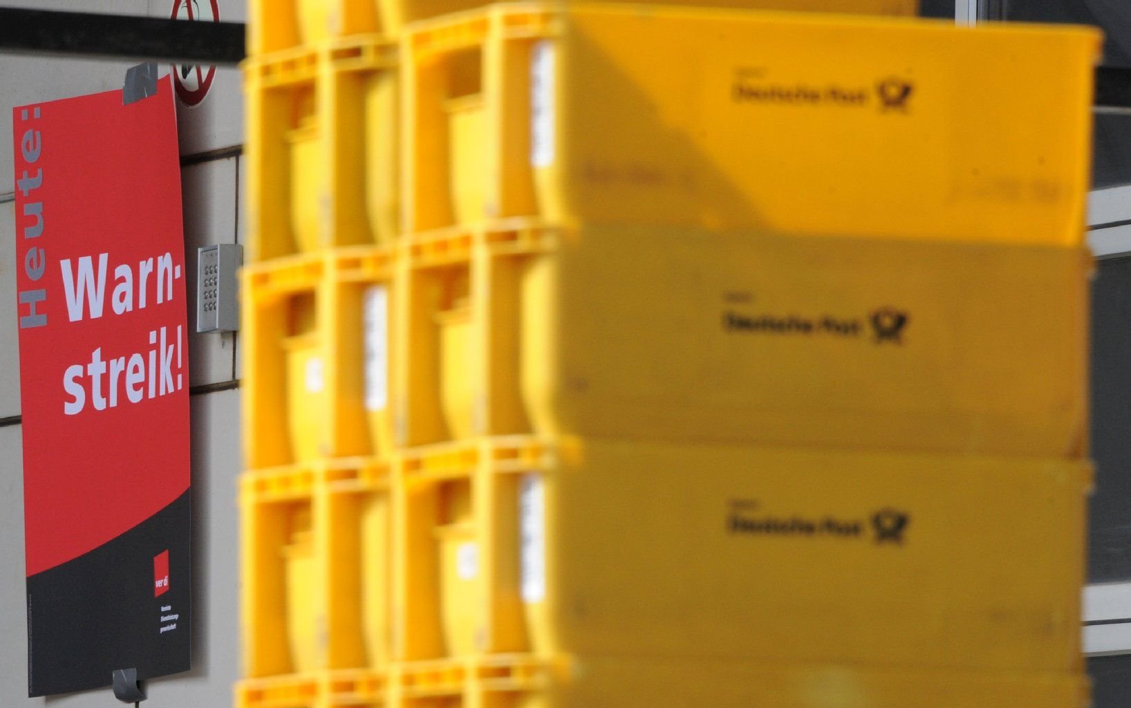 An einer Postvertriebsstelle stehen Postboxen vor einem Warnstreikplakat. Im Tarifstreit bei der Deutschen Post will die Gewerkschaft Verdi die Warnstreiks am 23. und 24.04. fortsetzen.
