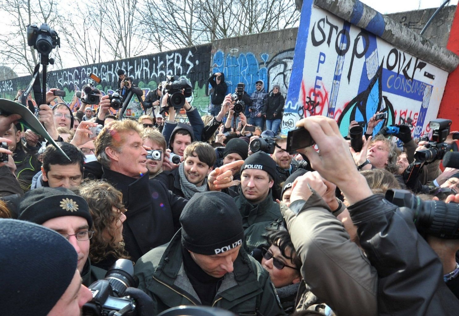 Umringt von Demonstranten und Polizisten, geht der amerikanische Schauspieler und Sänger David Hasselhoff in Berlin zur East Side Gallery, einem künstlerisch gestalteten Restabschnitt der früheren Berliner Mauer.