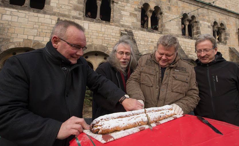 Oberbürgermeister Frank Ruch, Pfarrer Andreas Müller, Bäckermeister Ulrich Hecht und Ortsbürgermeister Manfred Kaßebaum (v. l. n. r.) schneiden den Weihnachtsstollen an.
