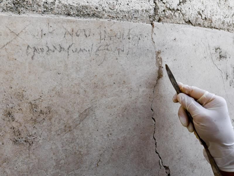 Ein Archäologe zeigt an einer Mauer in Pompeji die Kohle-Inschrift, die auf die Eruption des Vesuv im Jahr 79 verweist. Foto: Ciro Fusco/ANSA/AP
