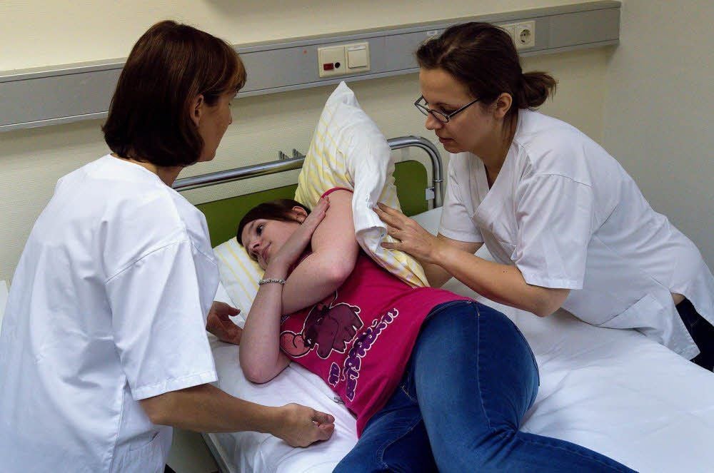 Ines Schiller (l.) erklärt die rückenschonende Lagerung von Patienten.