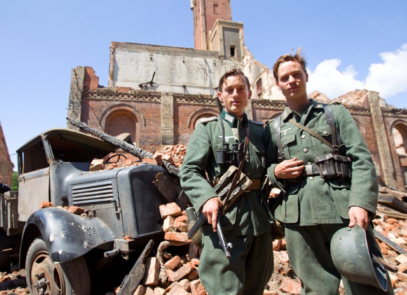 Der Schauspieler Volker Bruch (l) in der Rolle des «Wilhelm Winter» und der Schauspieler Tom Schilling als sein Bruder «Friedhelm Winter» stehen am 14.07.2011 bei den Dreharbeiten für den Film «Unsere Mütter, unsere Väter» auf dem Gelände der ehemaligen Hildebrandschen Mühle in Halle/Saale.
