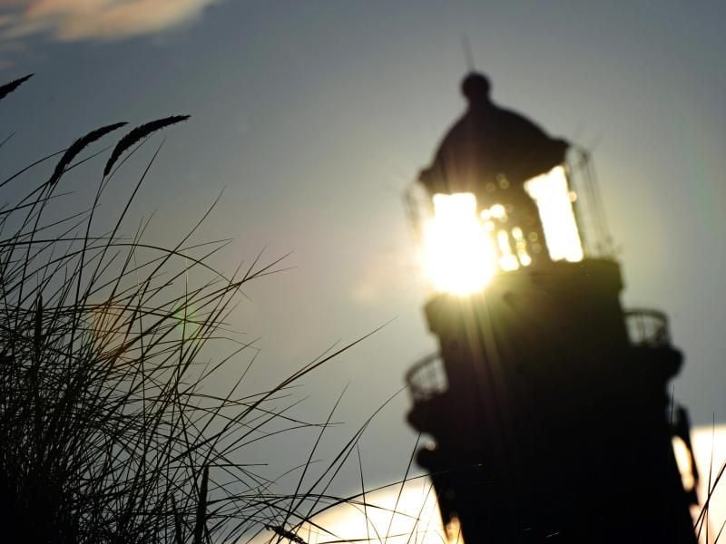 Die Sonne scheint durch den Leuchtturm Amrum. Foto: Daniel Reinhardt/dpa/Archivbild/Symbolbild
