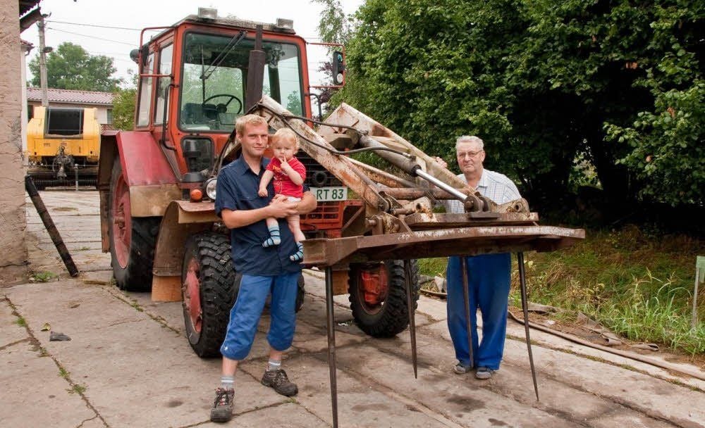 Torsten Ritter mit seinem Söhnchen Marvin und seinem Vater Willi vor dem Traktor, mit dem alles begann.